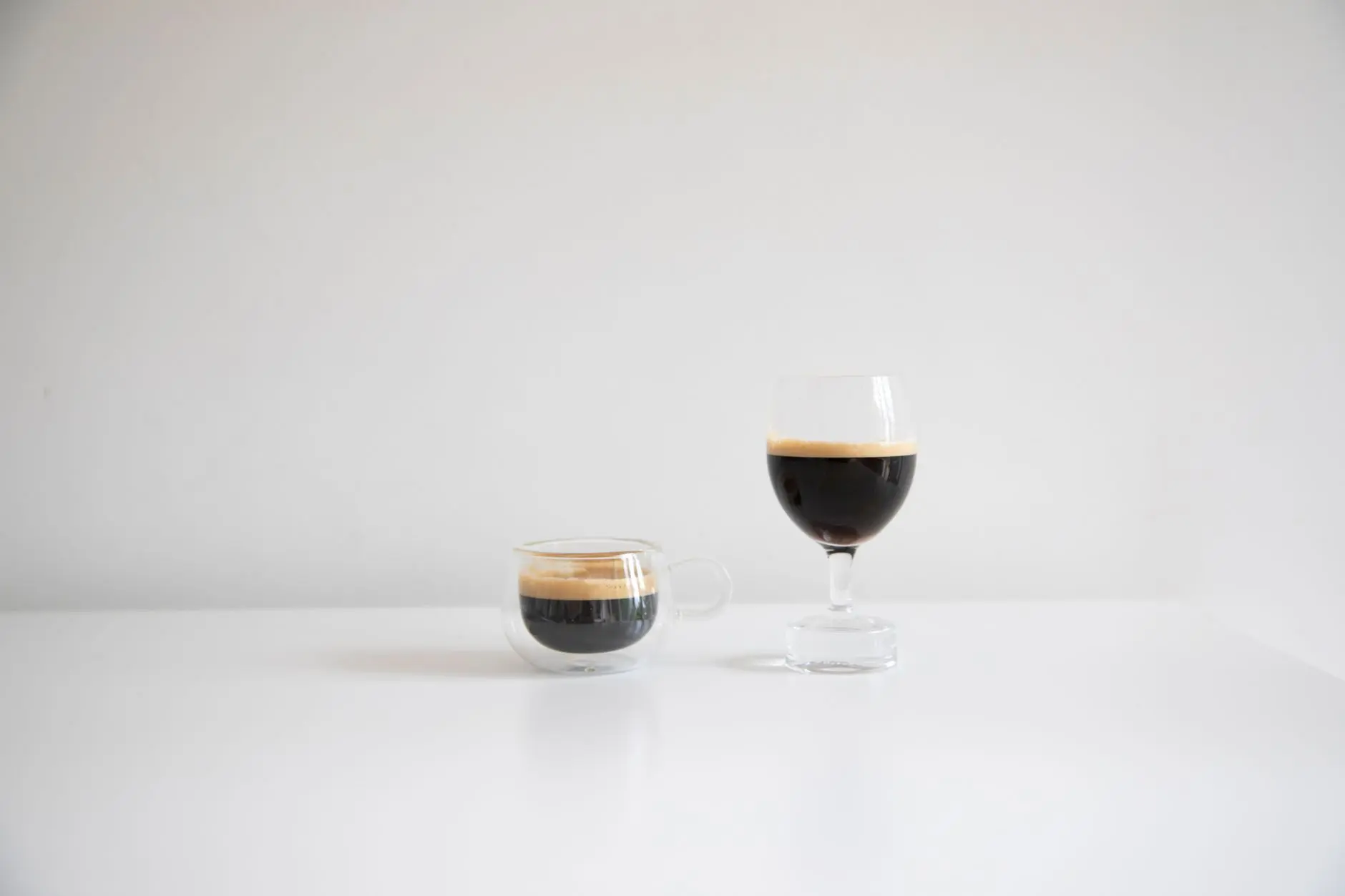 A glass hourglass with sand flowing through it, placed on a plain surface in soft daylight.